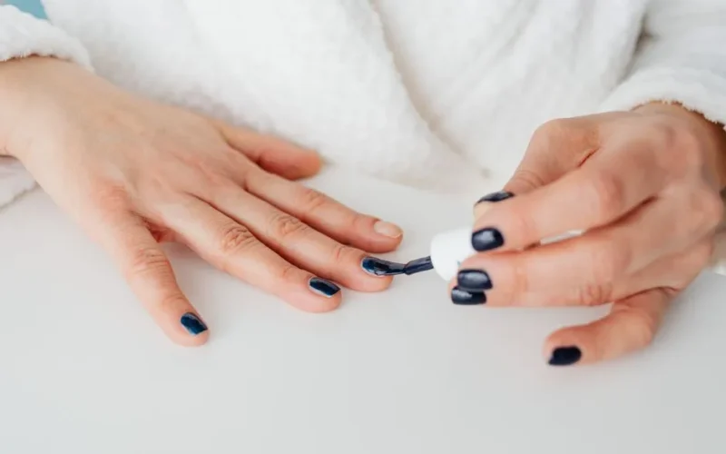 Close-up of a woman applying dark nail polish for a stylish manicure.