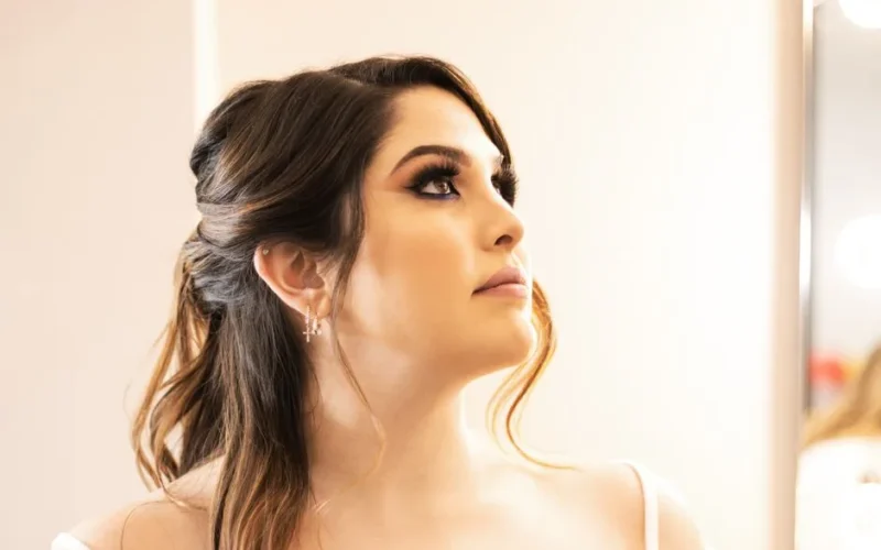 Close-up portrait of a woman with elegant makeup looking up indoors.