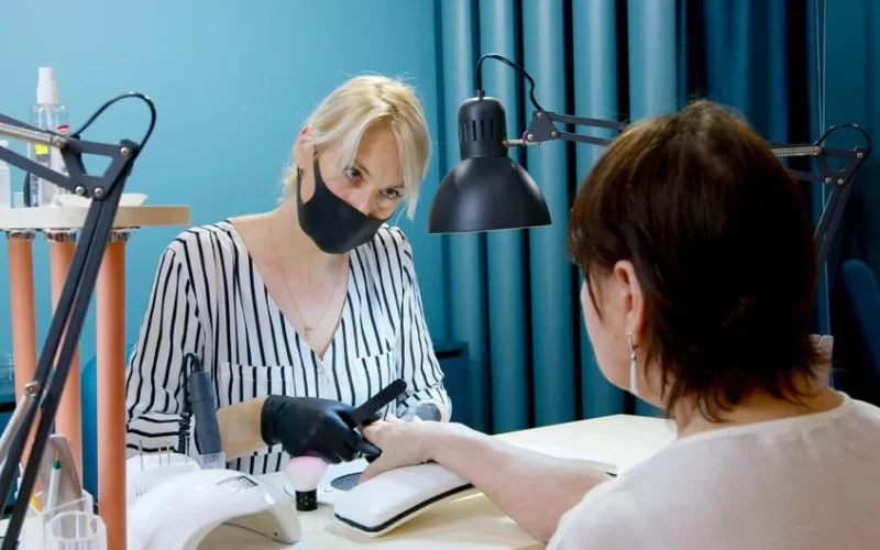 A manicurist professionally tending to a client’s nails in a modern salon.