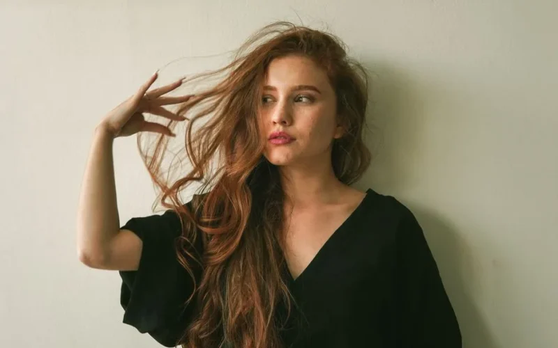 Portrait of a woman with long flowing hair in a relaxed indoor setting.